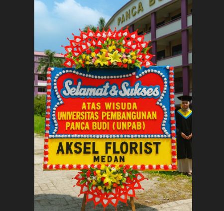 Papan bunga ucapan selamat wisuda UNPAB dari Aksel Florist Medan, dipajang di depan gedung kampus saat acara kelulusan.