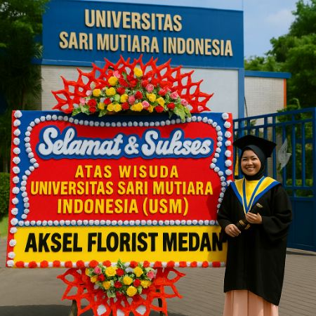 Wisudawan berdiri di samping papan bunga ucapan selamat di depan Universitas Sari Mutiara Indonesia (USM).